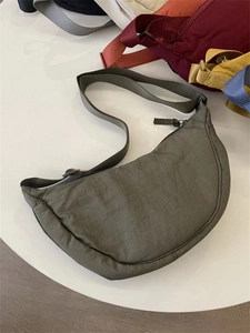 Overhead view of an olive green crescent nylon crossbody bag on a white display stand