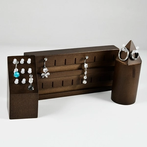 Macro detail of walnut wood jewelry display set with studs and rings on white background