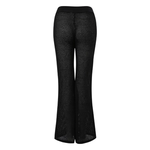 Detail of black knit sheer flared pants featuring crochet pattern and wide elastic waistband