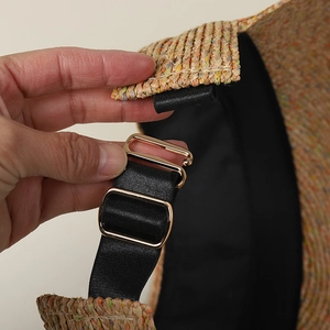 Close-up of adjustable black elastic strap and golden buckle on raffia straw sun hat