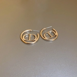 Macro shot of gold-plated metal geometric hoop earrings featuring a stylish D letter design