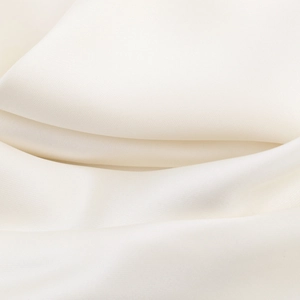 Detailed close-up of smooth cream satin fabric showing elegant drapes and soft silk texture