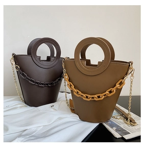 Detail view of brown bucket bags featuring round handles and thick decorative chains