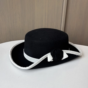 Détail d'un chapeau en feutre de laine avec fleur noire et bord blanc contrasté