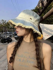 Detail view of denim bucket hat with frayed edges and blue gradient wash effect