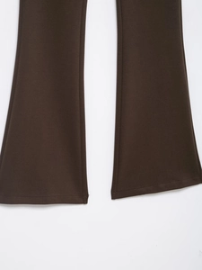 Detailed close-up of dark brown knit trousers showing the flared hem and fabric texture