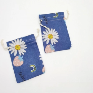 Detail view of cotton drawstring bags with white daisy and pink strawberry patterns