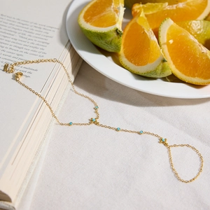 Detail der 18K Gold-Edelstahl-Handkette mit türkisfarbenen Perlen und Orangen-Deko