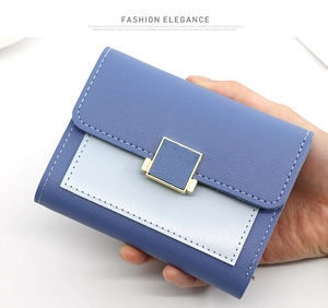 Détail d'un portefeuille en similicuir bleu avec boucle dorée et coutures blanches