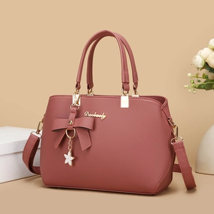 Elegant pink lychee texture handbag with bow decoration and floral pendant for women