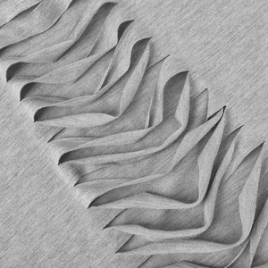 Detail view of medium gray knitted fabric with intricate 3D pleats and textured design