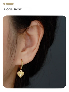 Close-up of golden S925 silver heart earring with center zircon on model's ear
