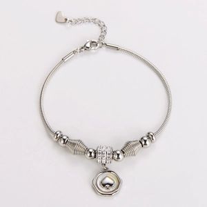 Detailed macro view of silver snake chain bracelet featuring heart pendant and beaded charms