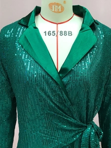 Dettaglio di un top verde scintillante con paillettes, lacci in vita e collo a revers