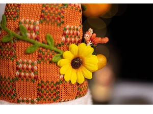 Close-up of knit gnome doll with orange plaid fabric and decorative sunflower