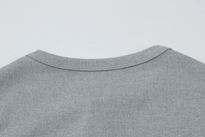 Gros plan détaillé sur le col en maille côtelée grise et les coutures de ce gilet tendance