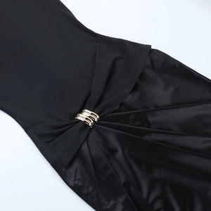 Détail de robe noire en satin avec empiècements et boucles décoratives en métal doré