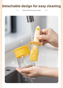 Detail of detachable duck-shaped silicone oil brush being rinsed under tap water for easy cleaning