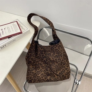 Detailed view of suede leopard print tote bag placed on a modern acrylic chair