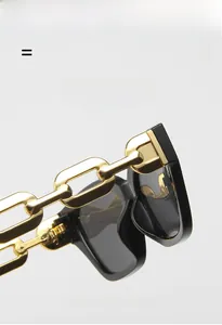Detailed macro shot of the cat-eye sunglasses featuring bold gold metal chain temples