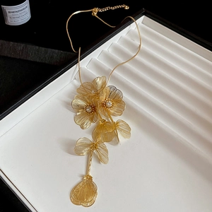 Close-up of golden hollow flower layered necklace on white display tray
