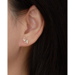 Close-up of elegant gold stud earrings with white pearls and sparkling zircons on model