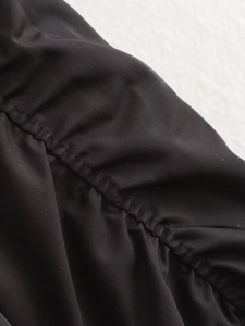 Vue détaillée du tissu noir avec texture plissée et coutures fines sur la veste