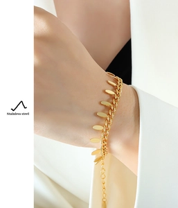 Detail of 18k gold plated stainless steel curb chain bracelet with leaf fringe charms