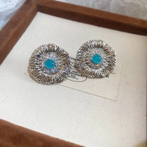 Macro detail of vintage silver flower stud earrings with a turquoise stone and white zircons