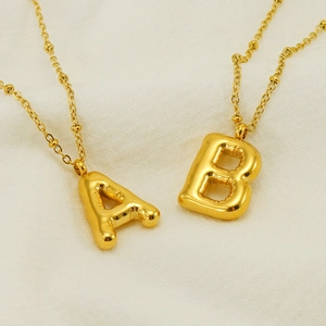 Polished 18K gold stainless steel bubble letter A and B necklaces on fabric
