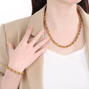 Polished gold stainless steel twist chain necklace and bracelet set worn by a model