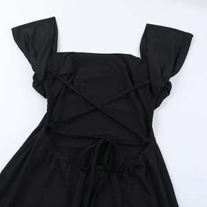 Detail of a black mini dress featuring a crisscross back tie design and ruched texture