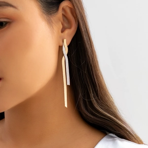 Detail view of two-tone gold and silver snake chain tassel earrings on a model