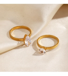 Detailed macro of gold-plated rings with marquise and round zircon on satin