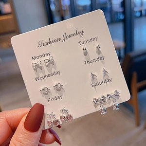 6 pairs of silver earrings set with butterfly and heart designs on a white card display