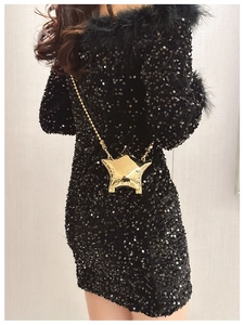 Golden star-shaped metal crossbody bag with chain strap styled on a black sequin dress