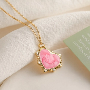 Macro detail of gold heart pendant with pink enamel texture and sparkling cubic zirconia