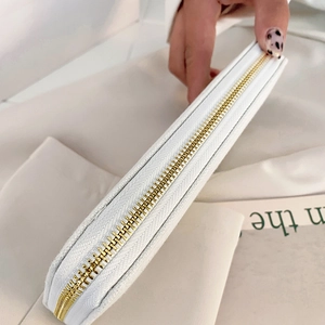 White canvas clutch bag with gold zipper detail and spacious interior for women