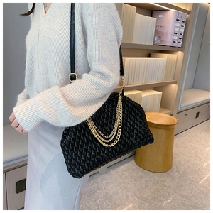 Detail of black woven shoulder bag with triple gold chains and leather strap
