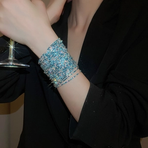 Multi-layer lake blue crystal rhinestone stretch bracelet on woman's wrist with wine glass