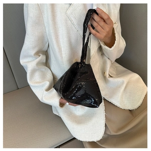 Sac à main tendance à paillettes noires en forme de triangle tenu par un mannequin