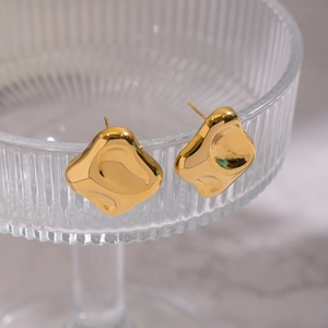 Macro detail of irregular 18K gold plated stainless steel stud earrings on glass