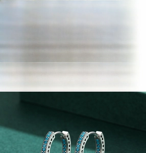 Macro detail of S925 silver hoop earrings featuring turquoise inlay and hollow heart designs