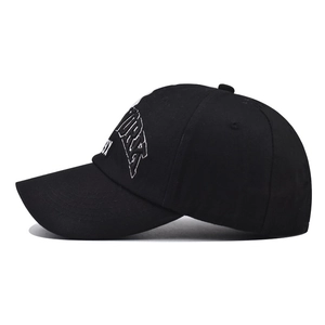 Close-up of white NEW YORK embroidery and side stitching on a washed black cotton baseball cap