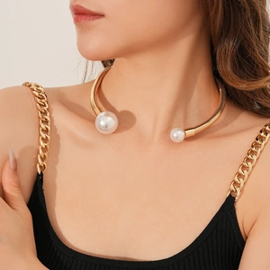 Close-up of elegant gold collar necklace featuring two large white pearls on a model