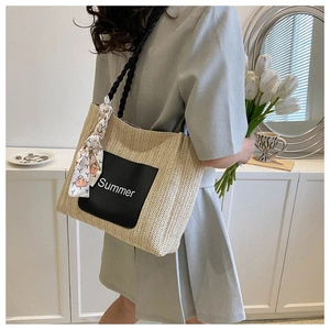 Détail d'un sac cabas en paille tissée avec patch Summer noir et foulard décoratif en soie