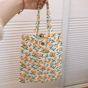 Détail du mini sac cabas en toile avec motifs d'oranges et fermeture par bouton pression
