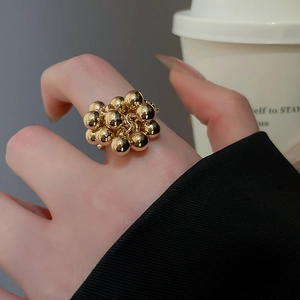 Detailed view of stacked golden spheres ring worn in a lifestyle city setting