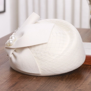 Detail view of white wool fascinator featuring mesh veil, bow and pearl accents