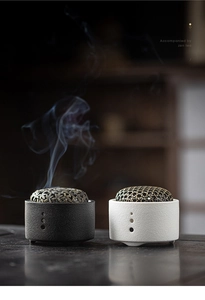 Detail of zen ceramic incense burner with hollow metal lid and rising smoke effect
